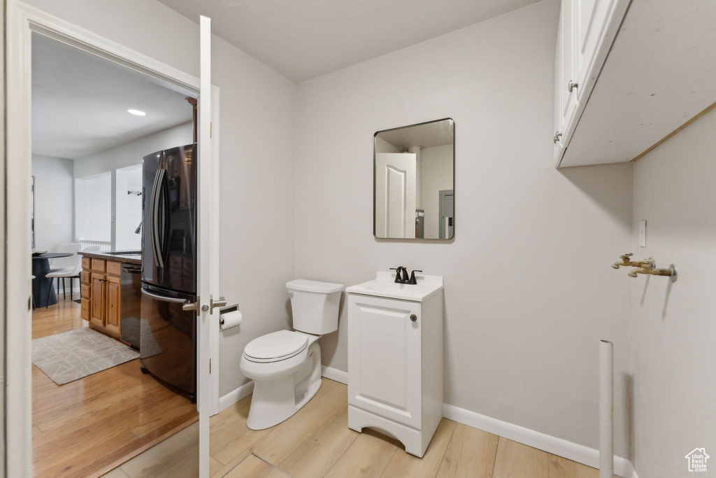 Bathroom with toilet, wood finished floors, vanity, and baseboards