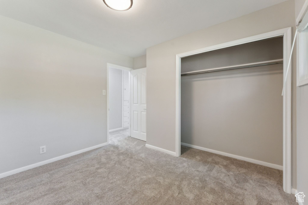 Unfurnished bedroom with carpet floors, a closet, and baseboards