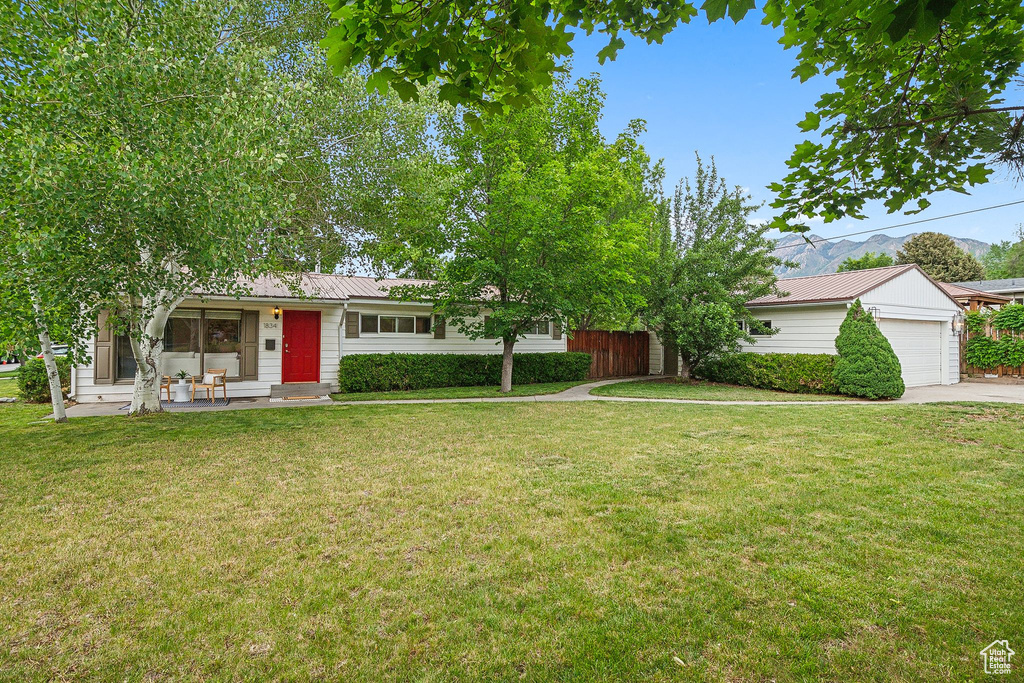 Ranch-style home featuring a front yard, metal roof, and concrete driveway
