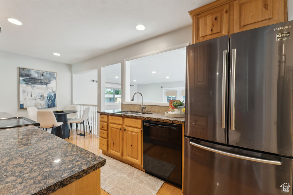 Kitchen featuring freestanding refrigerator, dishwasher, a sink, light wood-style flooring, and recessed lighting
