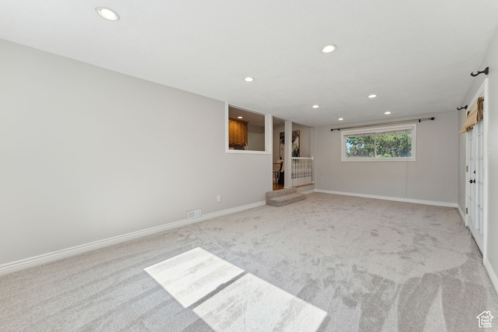 Unfurnished living room with light colored carpet, recessed lighting, and baseboards