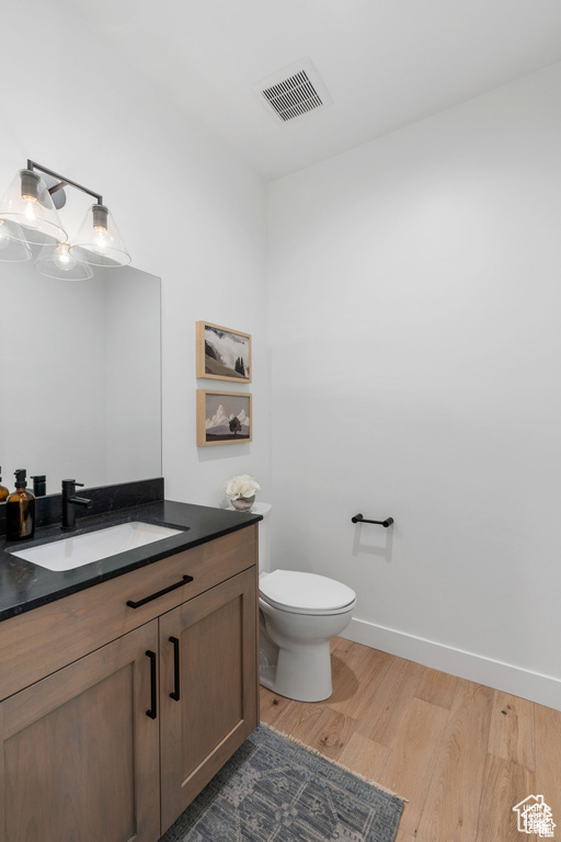 Bathroom with vanity, wood finished floors, toilet, and baseboards