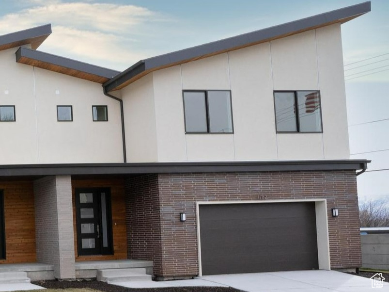 Contemporary home featuring a garage, brick siding, and driveway