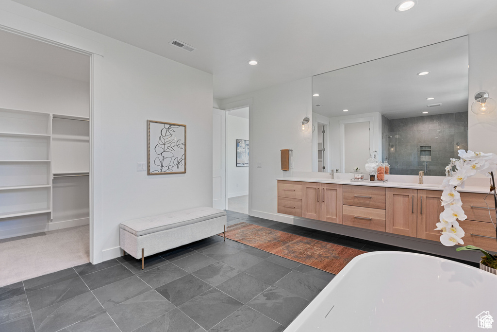 Bathroom featuring double vanity, a stall shower, a freestanding bath, recessed lighting, and tile patterned floors