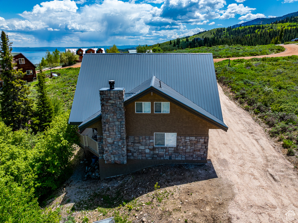 View of home\\\\\\\\\\\\\\\'s exterior with stone siding, metal roof, a chimney, stucco siding, and a balcony
