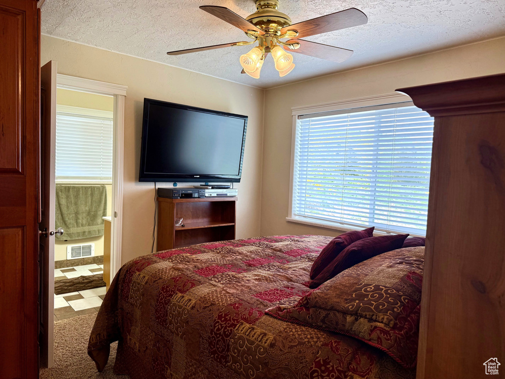Bedroom featuring a textured ceiling, connected bathroom, and a ceiling fan