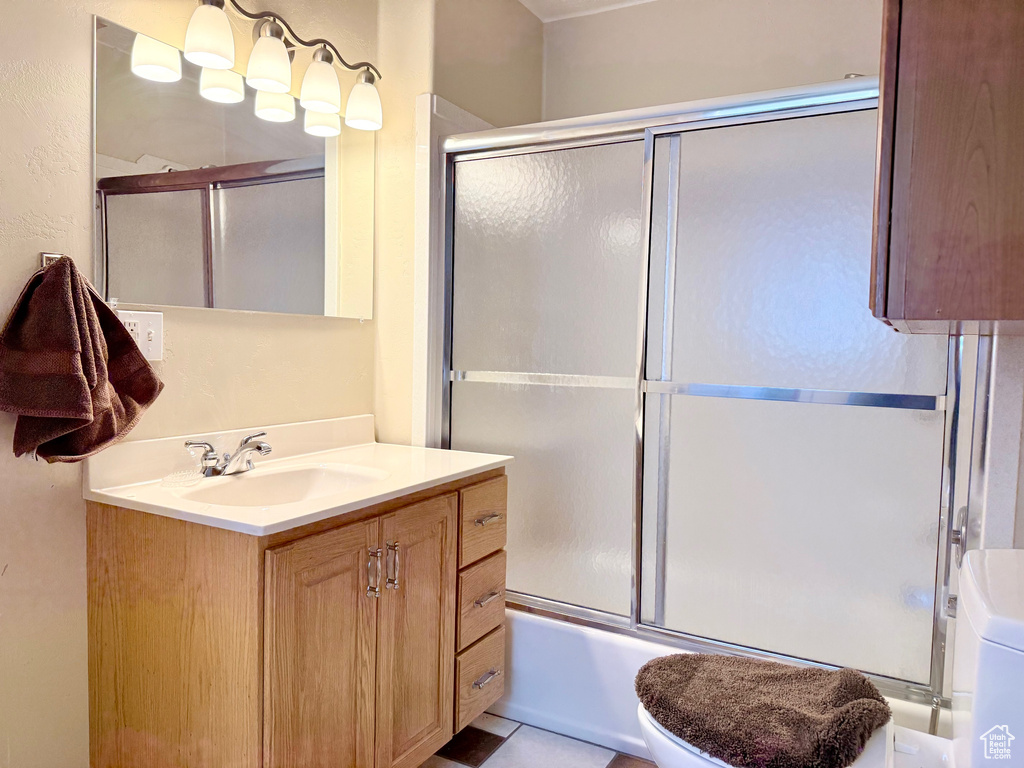 Bathroom featuring vanity, shower / bath combination with glass door, and toilet