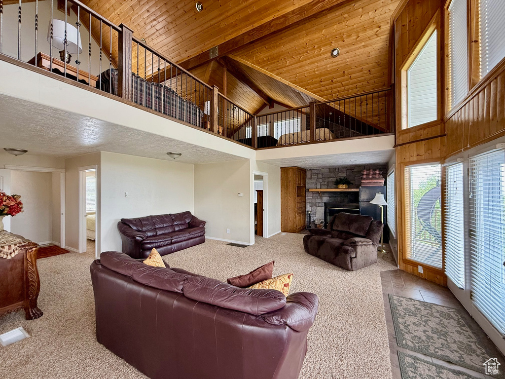 Living room with carpet, high vaulted ceiling, baseboards, wood ceiling with exposed beams, and a fireplace