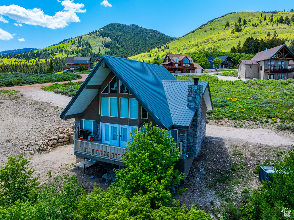 Rear view of property featuring a mountain view, a chimney, metal roof, and a standing seam roof