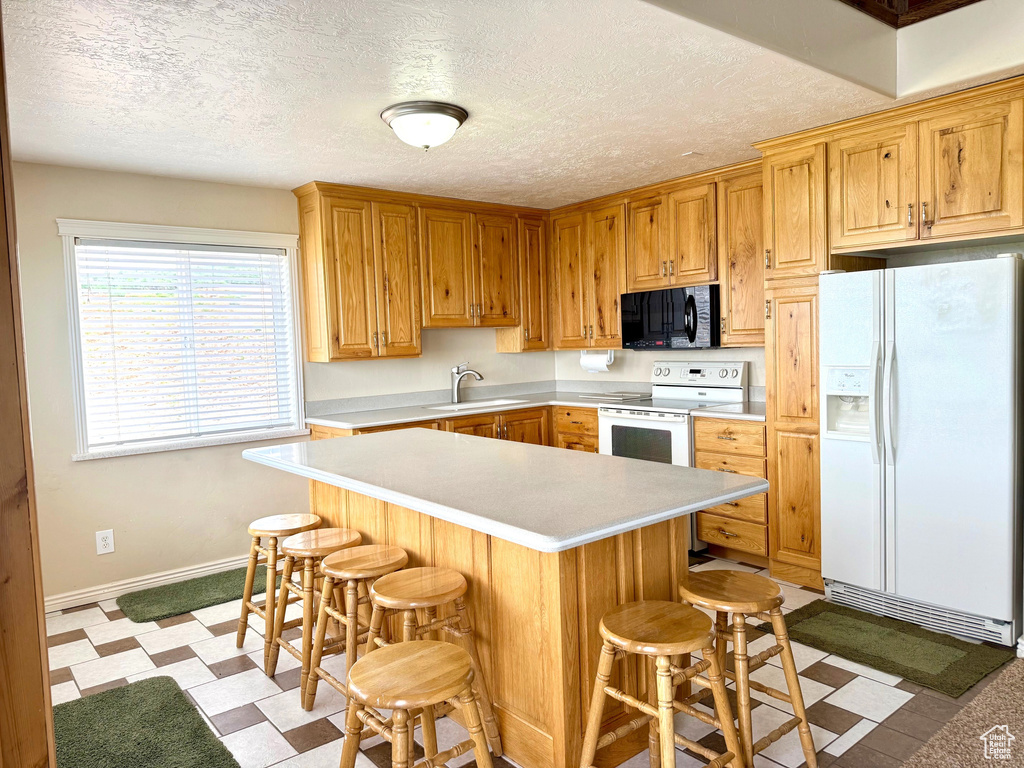 Kitchen featuring white appliances, light countertops, light flooring, baseboards, and a sink