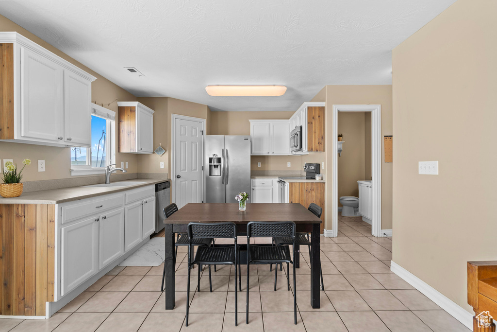 Kitchen featuring stainless steel appliances, a sink, white cabinets, and light tile patterned floors