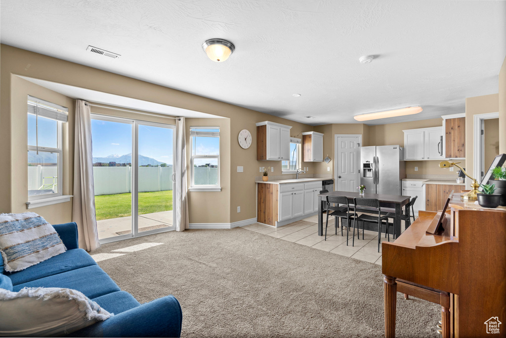 Living area featuring baseboards, light tile patterned flooring, and light carpet