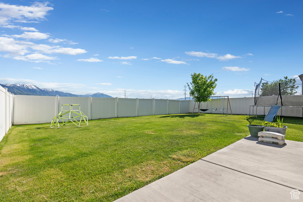 View of yard featuring a trampoline, a patio, and a mountain view