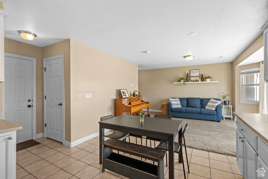 Dining area featuring light tile patterned flooring, baseboards, and a textured ceiling
