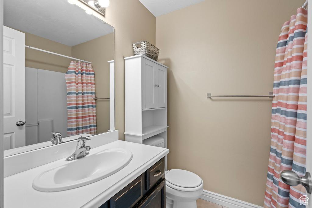 Full bathroom with vanity, toilet, a shower with shower curtain, tile patterned floors, and baseboards