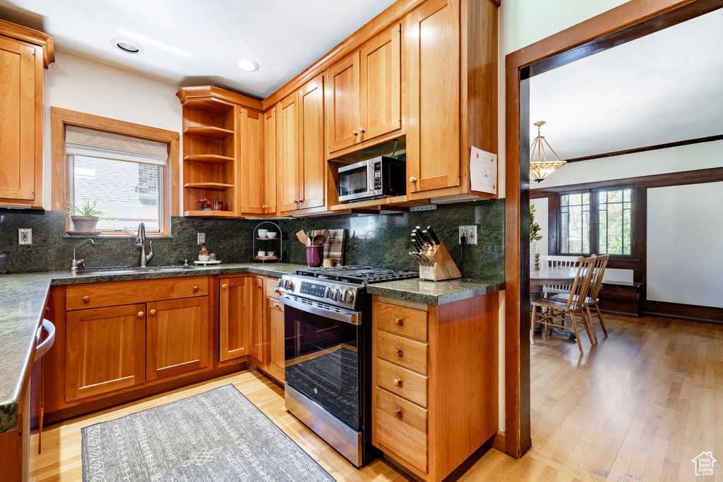 Kitchen featuring appliances with stainless steel finishes, light wood finished floors, open shelves, tasteful backsplash, and recessed lighting