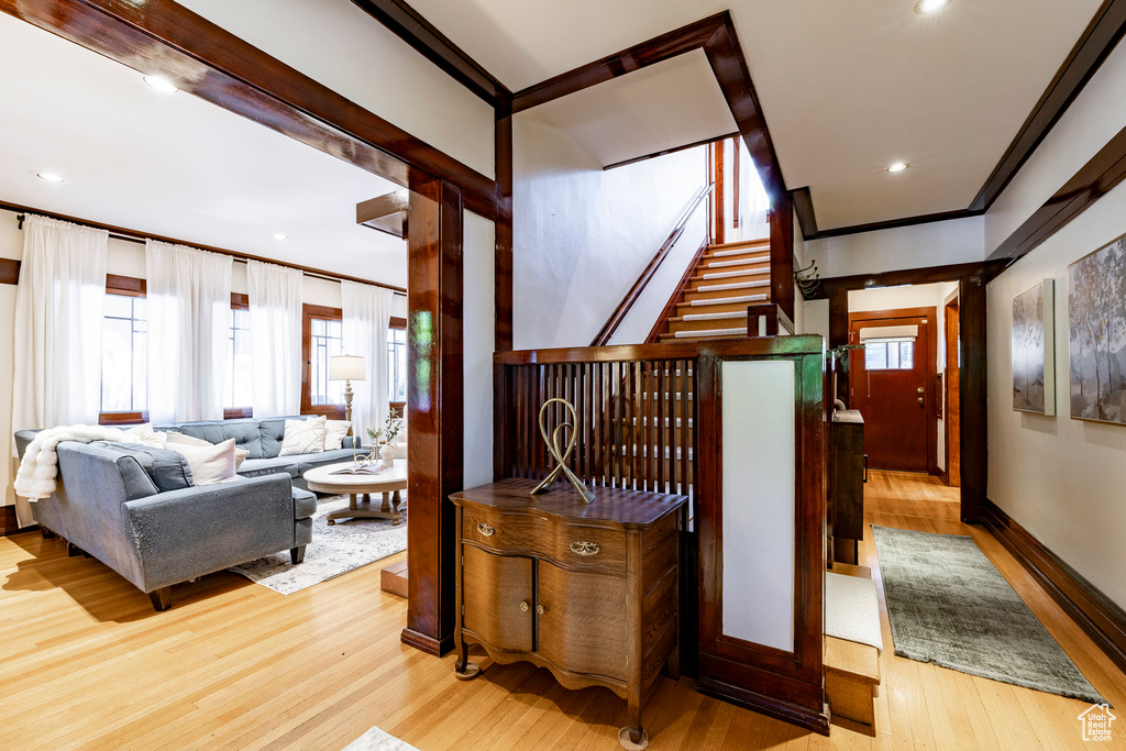 Stairs with wood finished floors, recessed lighting, and crown molding
