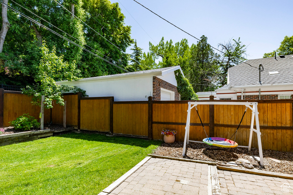 Fenced backyard featuring a garage and a patio area