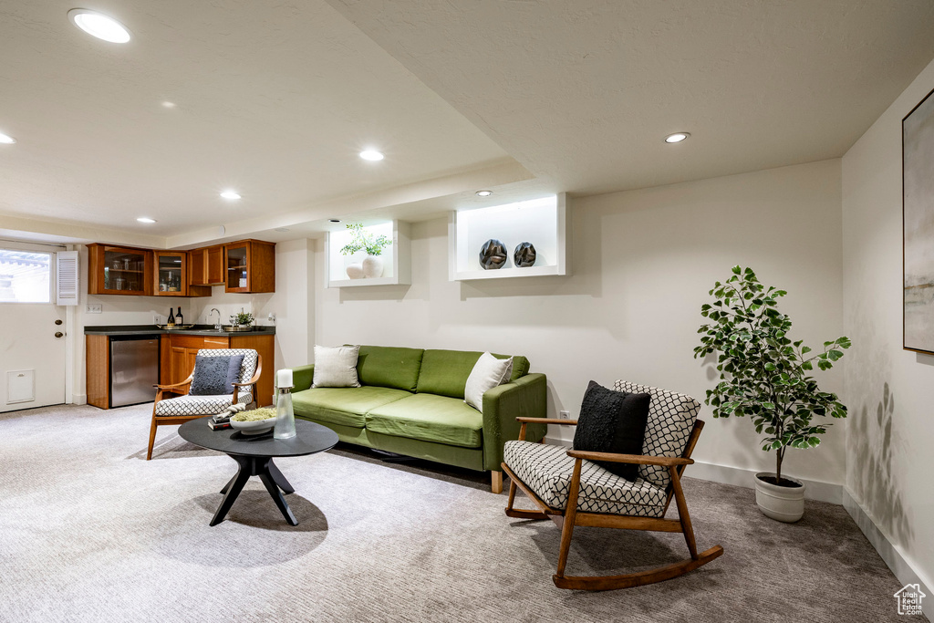Living room featuring bar with sink, light colored carpet, and recessed lighting