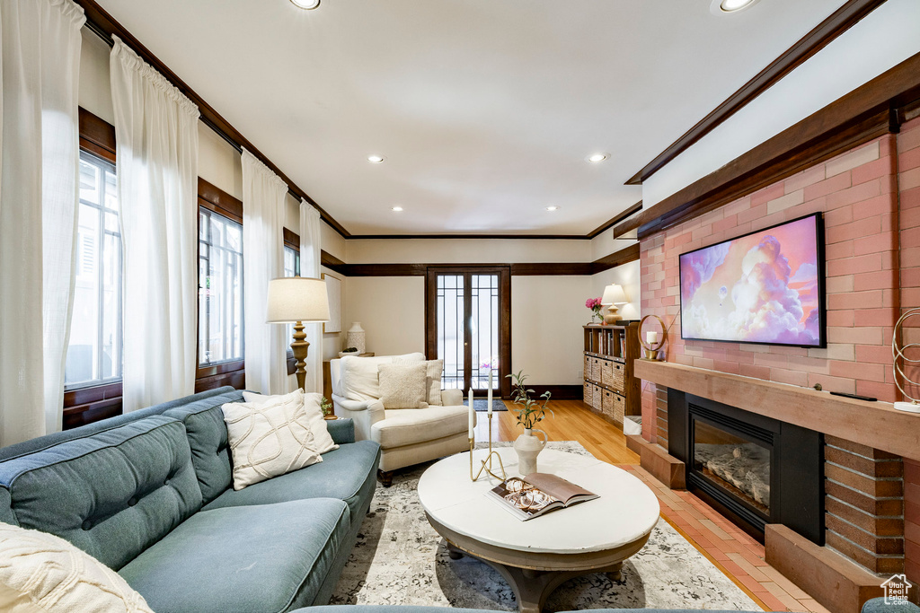 Living room with crown molding, a fireplace, recessed lighting, and light wood-style floors