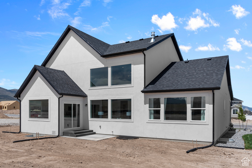 Rear view of property featuring roof with shingles, stucco siding, and a mountain view