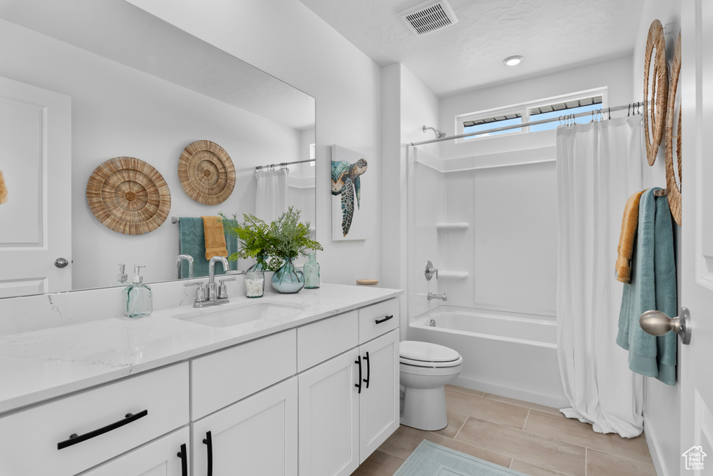 Bathroom with vanity, shower / tub combo with curtain, and toilet