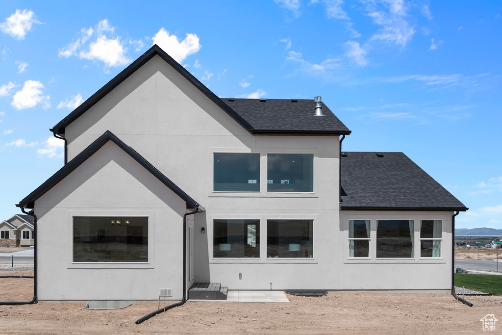 Back of property featuring roof with shingles and stucco siding