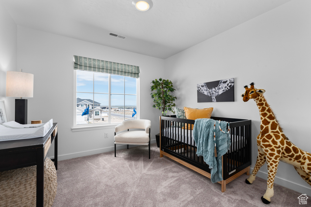 Carpeted bedroom with baseboards and a nursery area