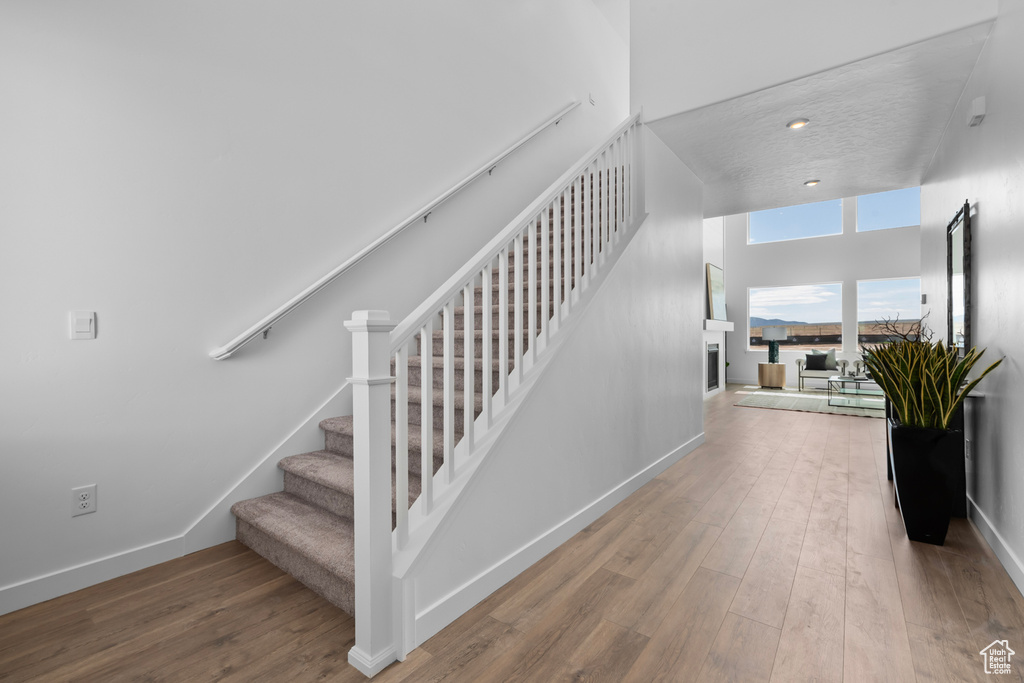 Staircase featuring wood finished floors, baseboards, and a fireplace