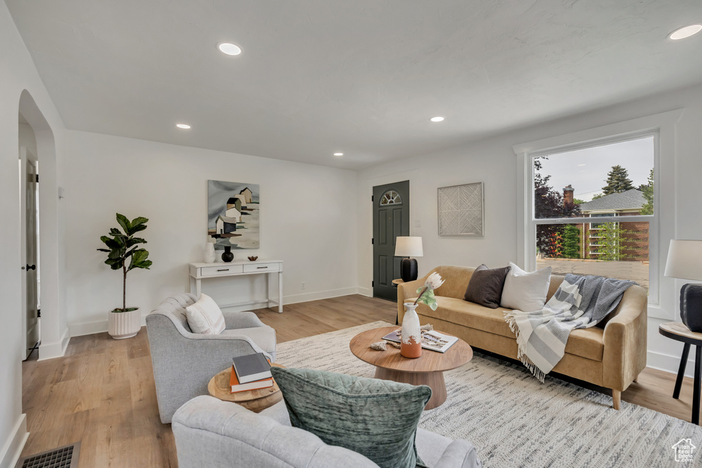 Living area with arched walkways, light wood-style floors, recessed lighting, and baseboards