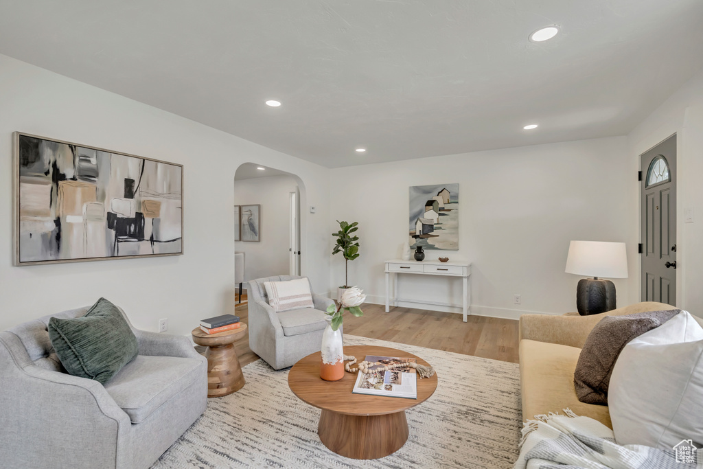 Living room with arched walkways, wood finished floors, recessed lighting, and baseboards