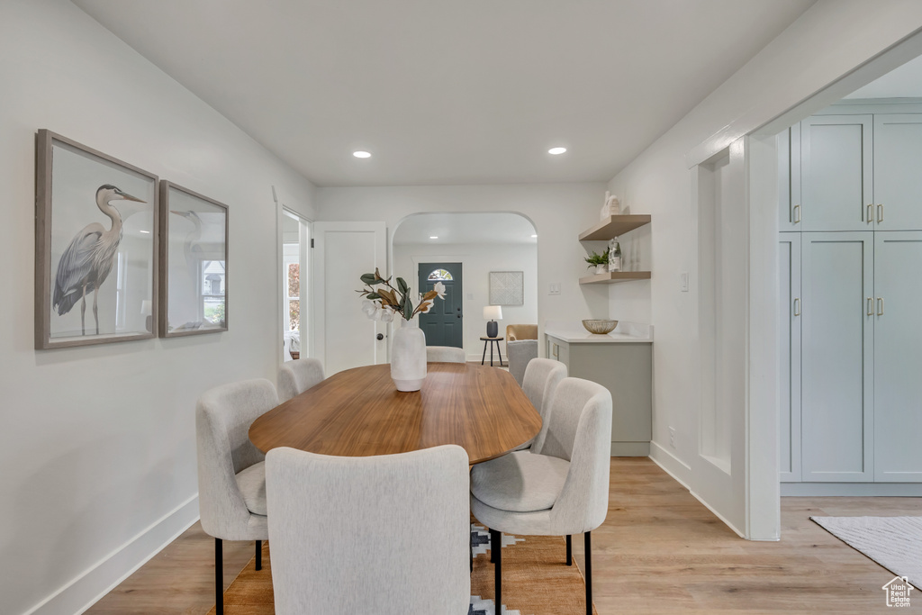 Dining space featuring arched walkways, light wood-style floors, recessed lighting, and baseboards