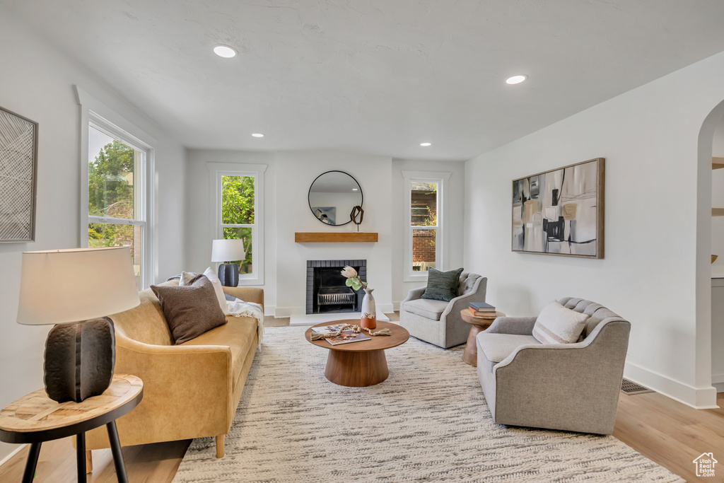 Living room with arched walkways, recessed lighting, wood finished floors, a fireplace, and baseboards