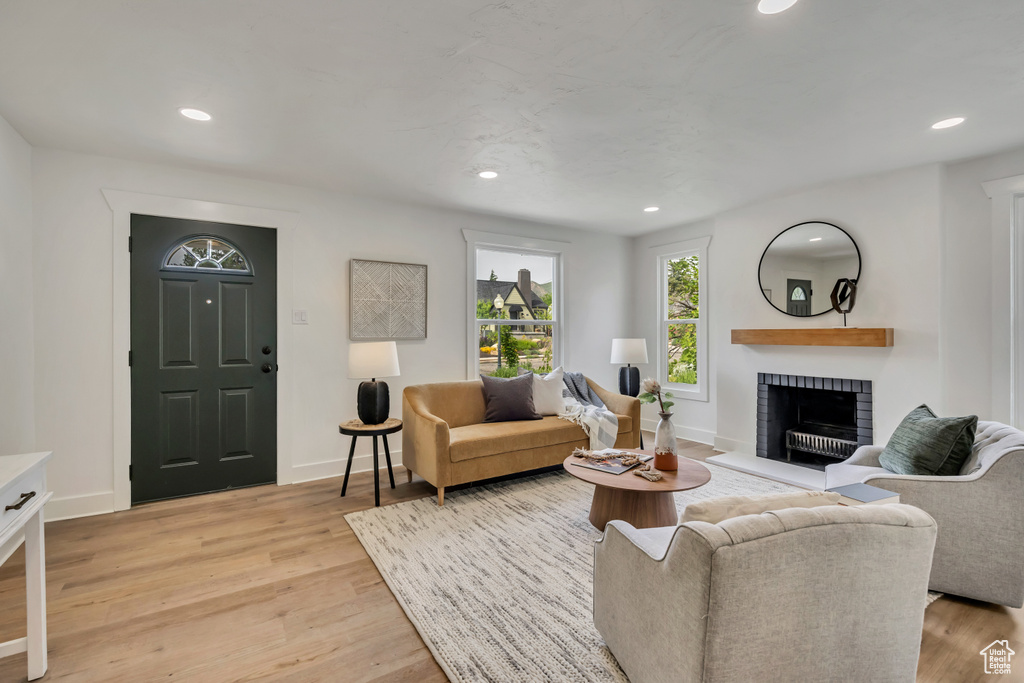 Living area featuring a brick fireplace, recessed lighting, light wood-style flooring, and baseboards