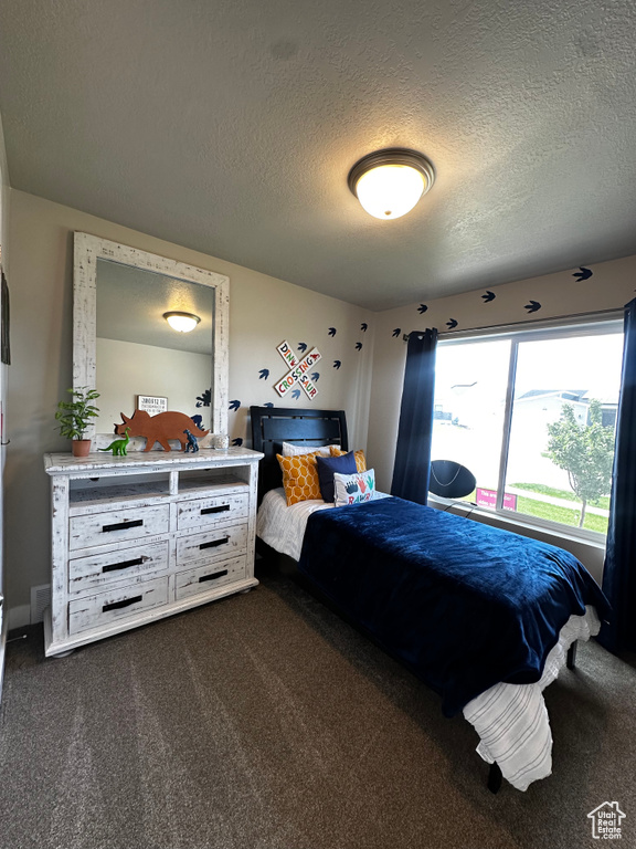 Bedroom featuring a textured ceiling and dark colored carpet