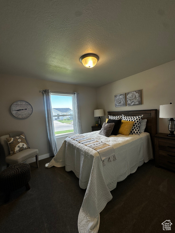 Carpeted bedroom featuring a textured ceiling and baseboards