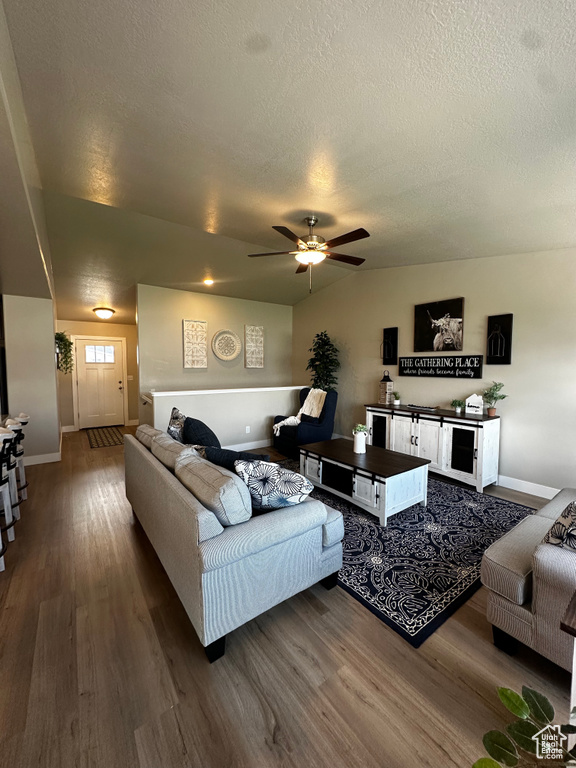 Living area featuring wood finished floors, baseboards, ceiling fan, and a textured ceiling