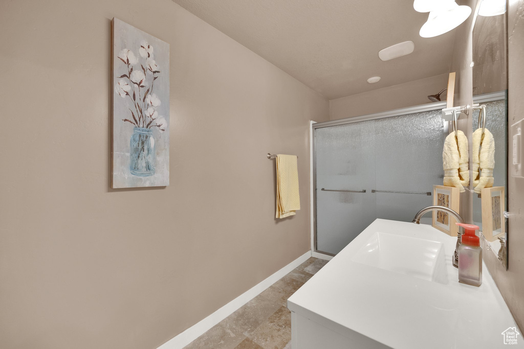 Full bathroom with a shower with door, vanity, and baseboards