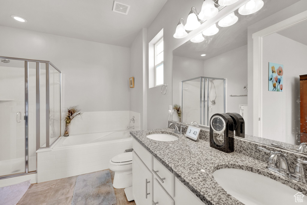 Full bath featuring a stall shower, double vanity, a garden tub, and toilet
