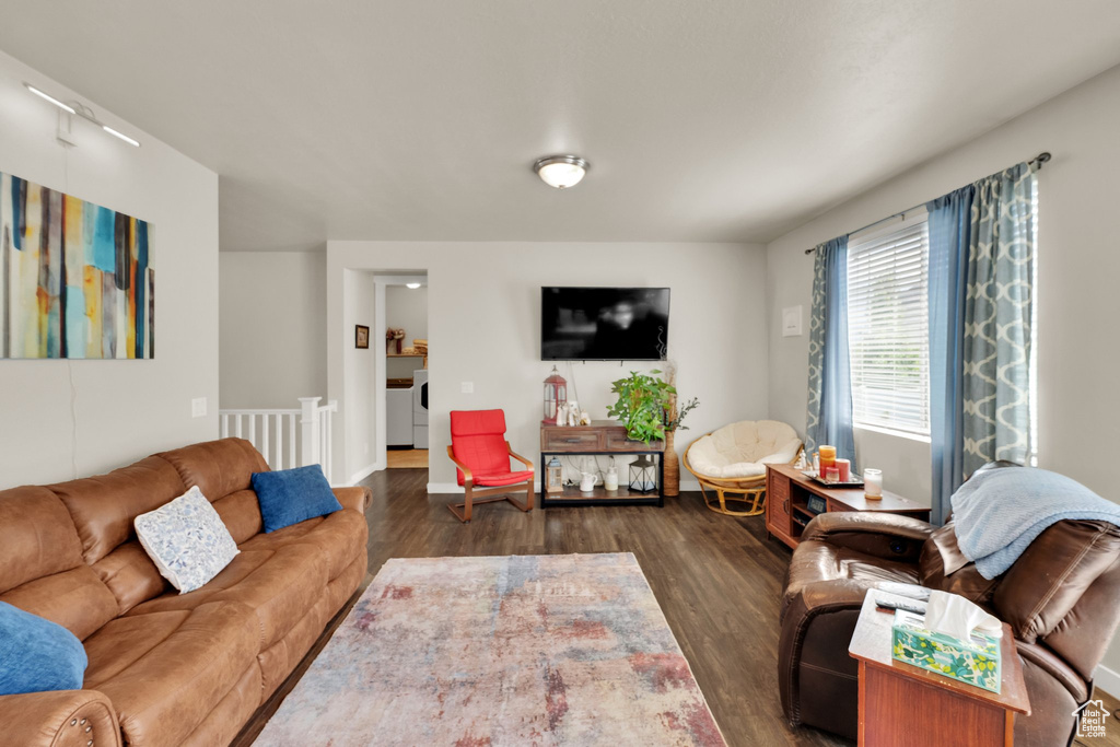 Living area featuring washing machine and dryer, dark wood-style flooring, and baseboards