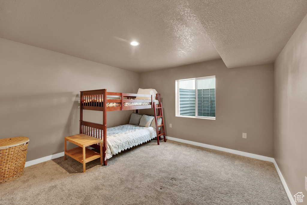 Carpeted bedroom with baseboards and a textured ceiling