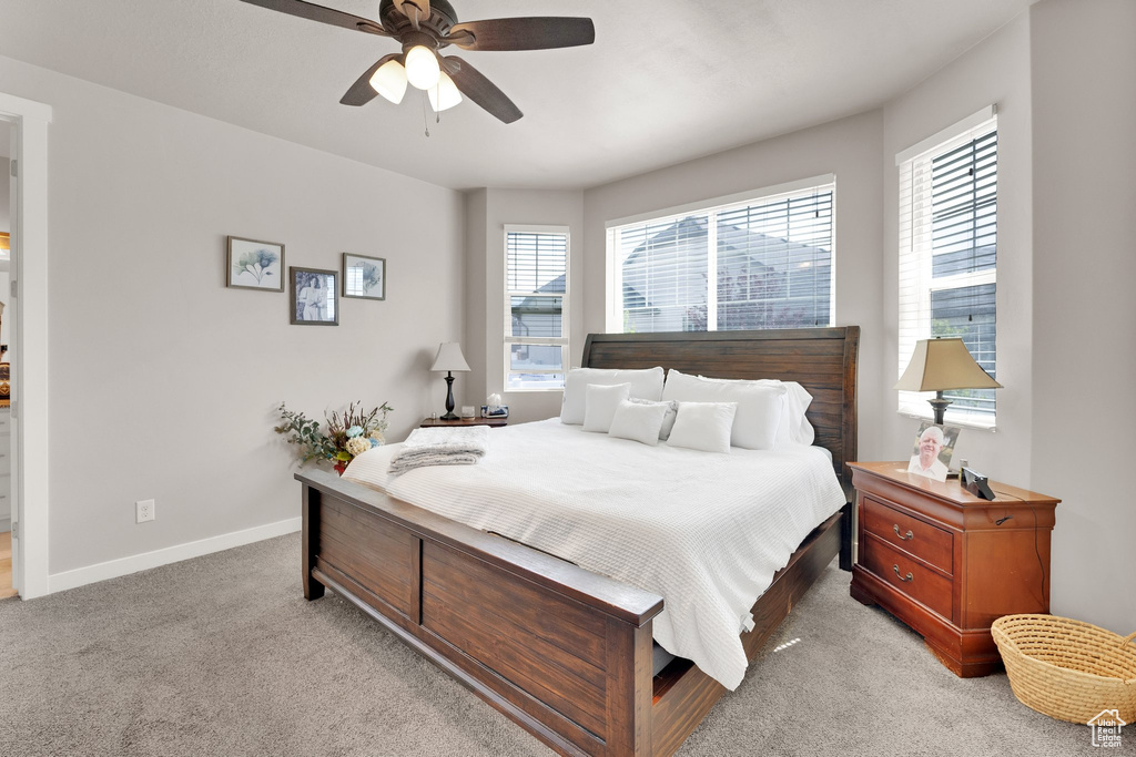 Bedroom featuring light colored carpet, baseboards, and a ceiling fan