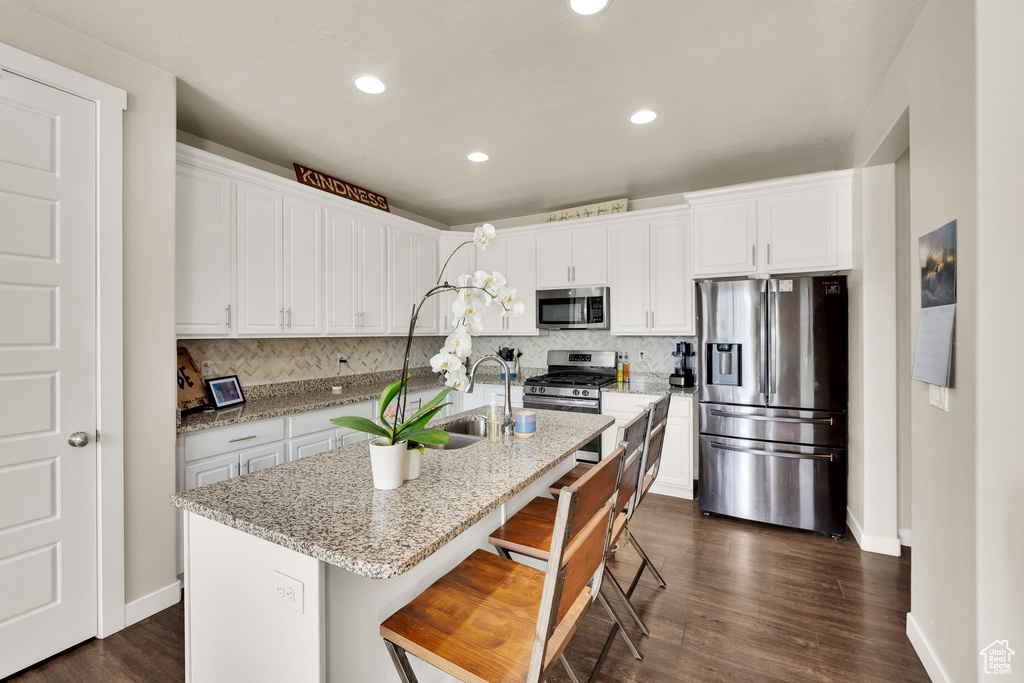 Kitchen with appliances with stainless steel finishes, baseboards, decorative backsplash, white cabinets, and recessed lighting
