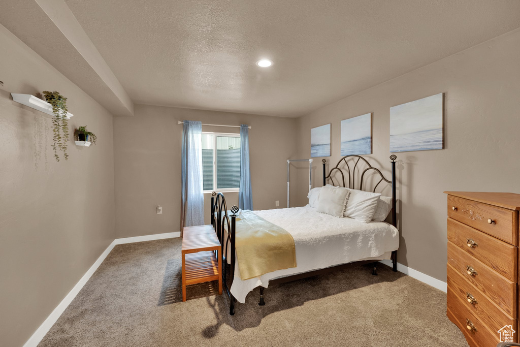 Carpeted bedroom featuring baseboards and a textured ceiling