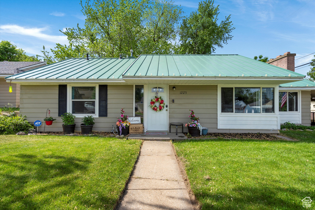 View of front of property with a standing seam roof, a front yard, and metal roof