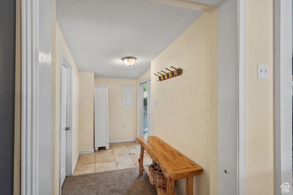 Hallway featuring light tile patterned flooring, baseboards, and light colored carpet