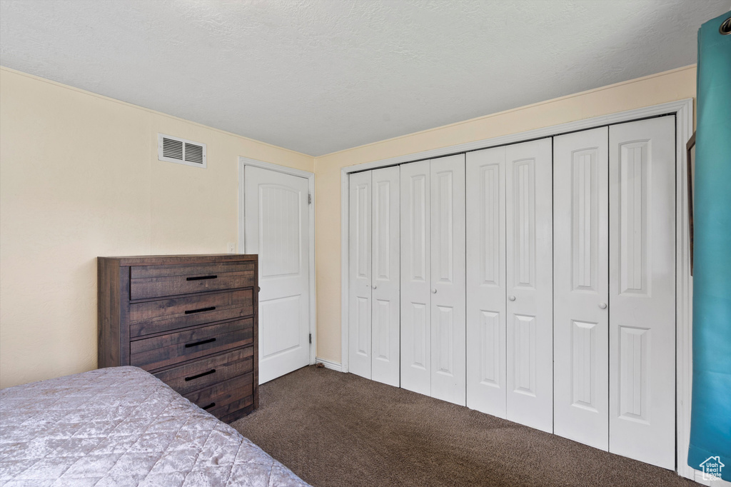 Bedroom with dark carpet and a closet