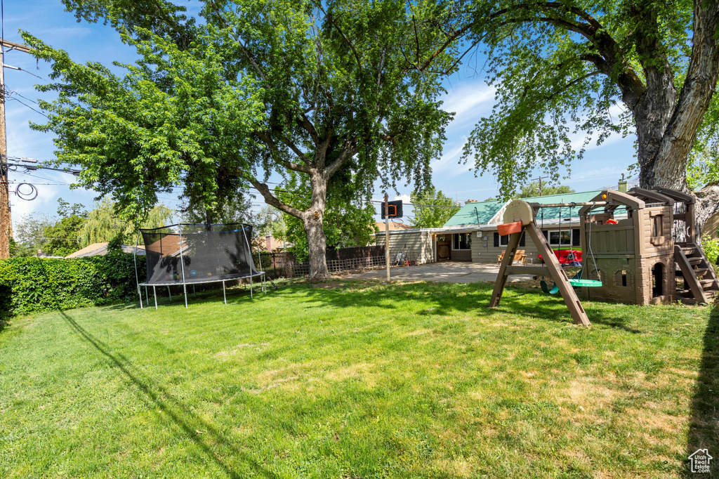 View of yard with a trampoline, a playground, and a patio