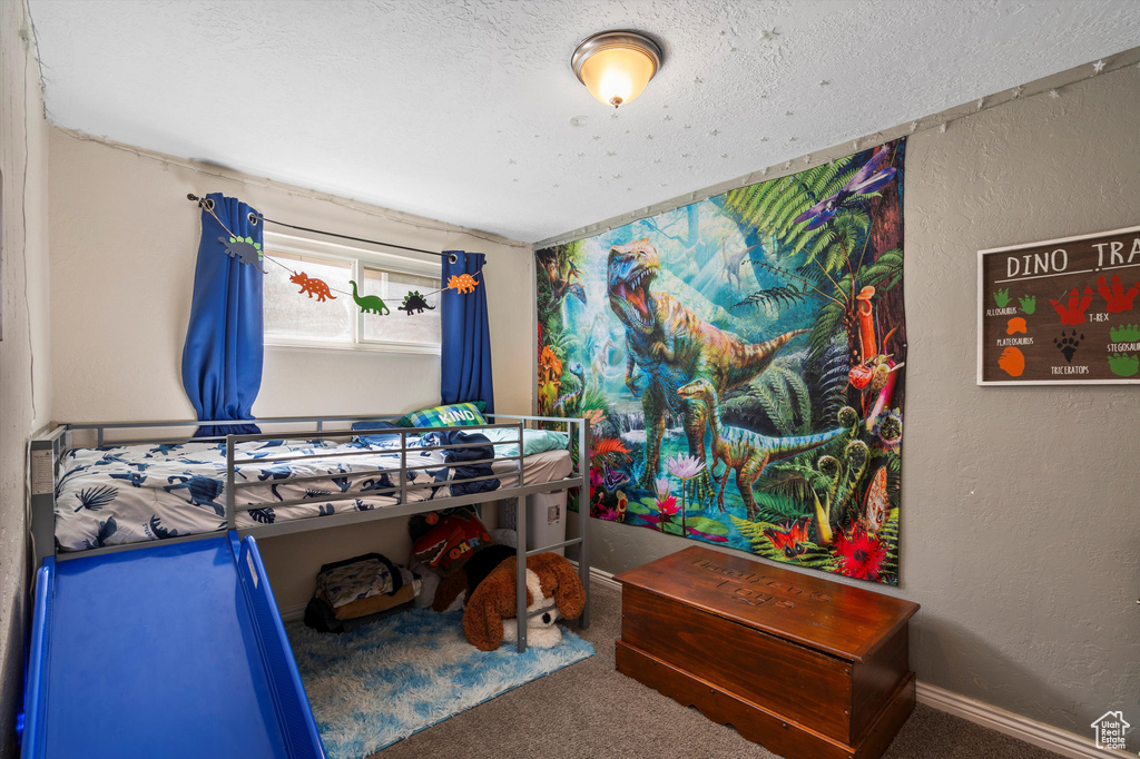 Bedroom with carpet floors, a textured wall, and a textured ceiling