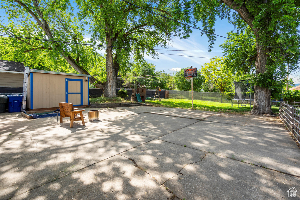 Fenced backyard featuring a trampoline and a patio area